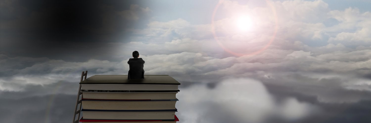 Man sitting on a pile of books above the clouds.