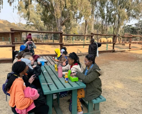 Snack time! Grades 4, 5 and 6 students taking a lunch break during a field trip to the Johannesburg Zoo in 2024.