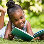 Little girl reading a book in the garden.